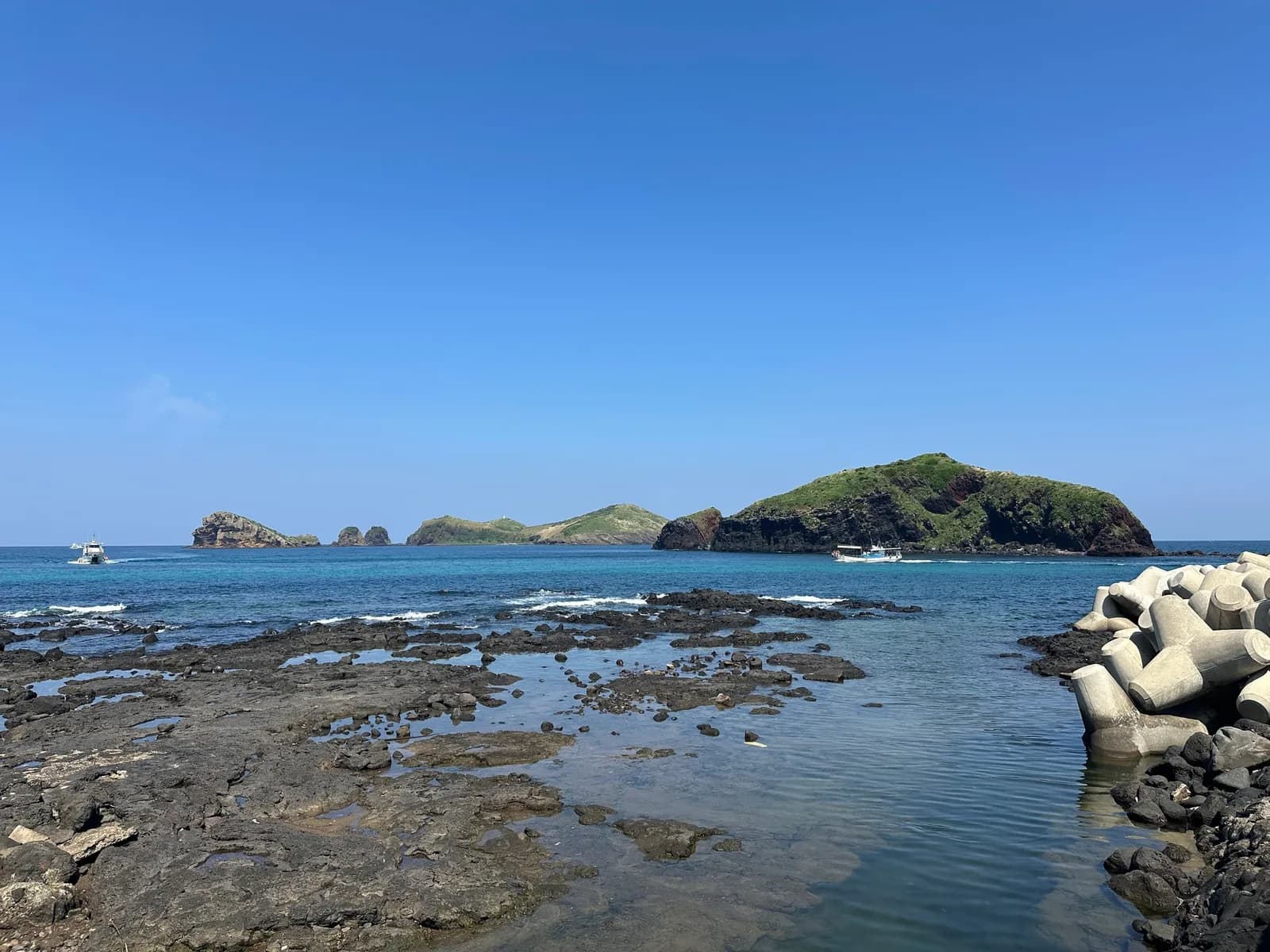 Chagwido and its small islands floating on the blue sea beyond a black basalt shore