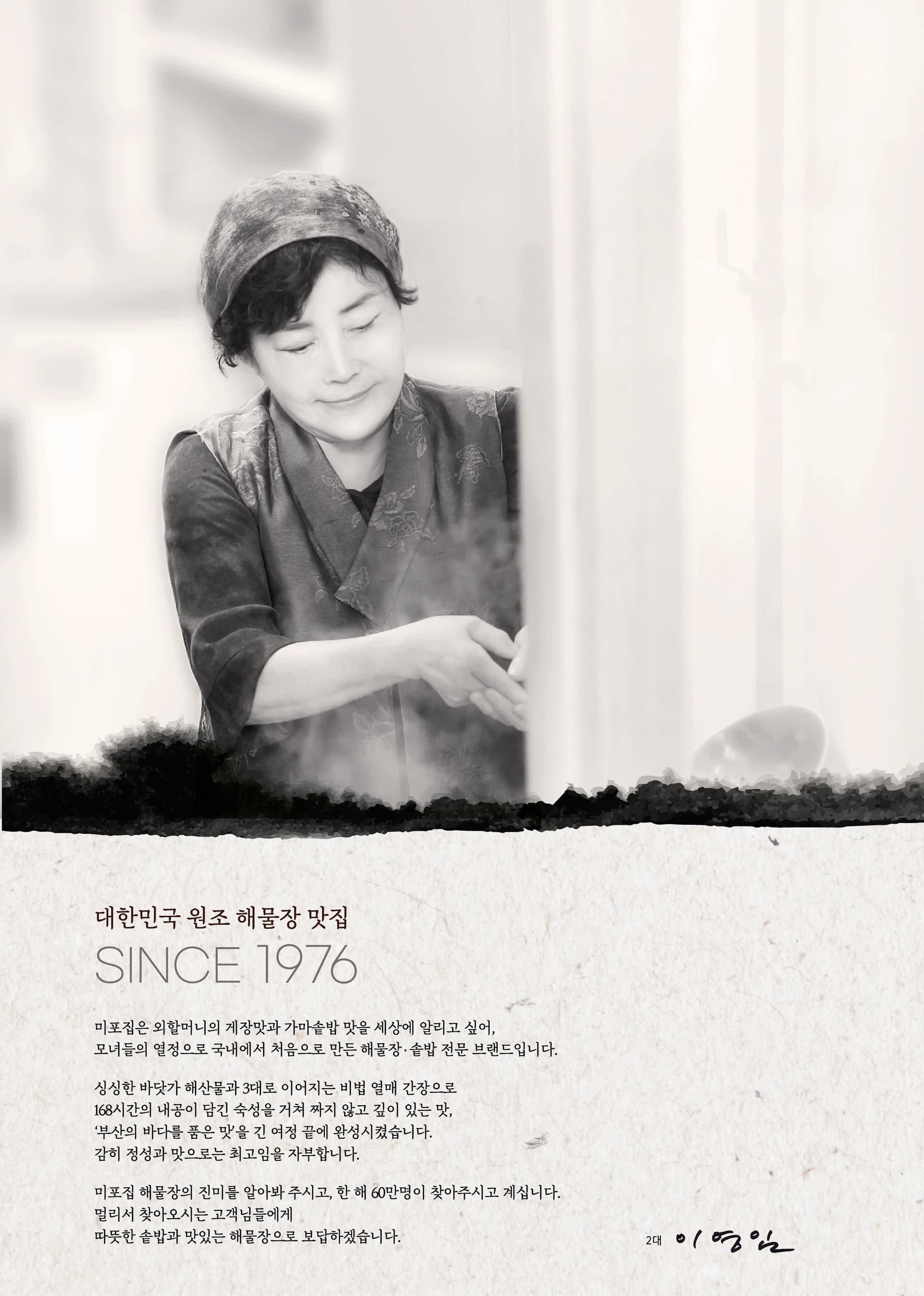 돌담에 걸린 흑백 인물 사진 액자와 짚으로 엮은 도구